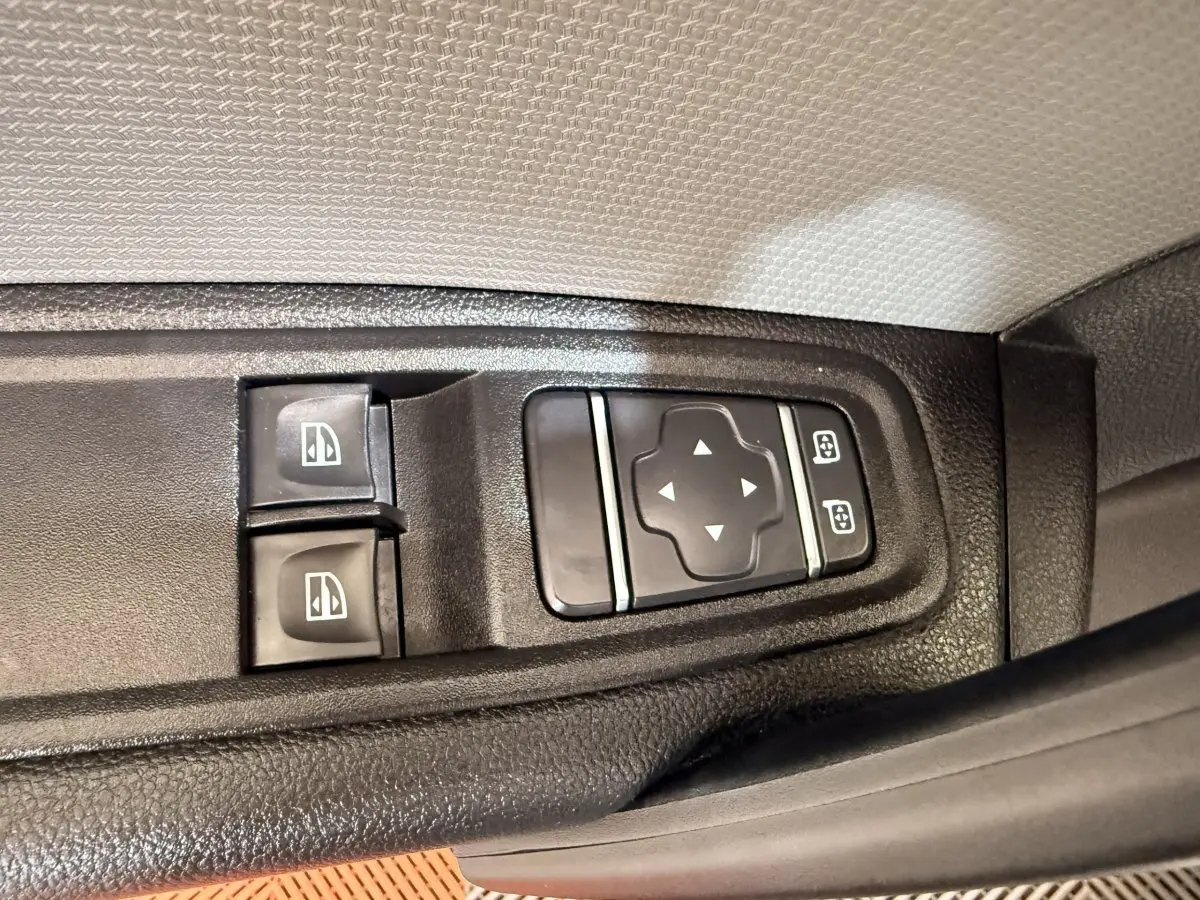 Gros plan sur les commandes des vitres et des rétroviseurs du côté conducteur d’un Renault Kangoo blanc 2022.