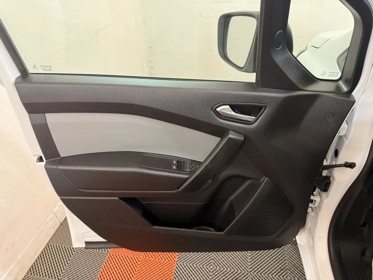 Vue intérieure de la porte avant gauche du Renault Kangoo blanc 2022, avec commandes de vitres et poignée noire.