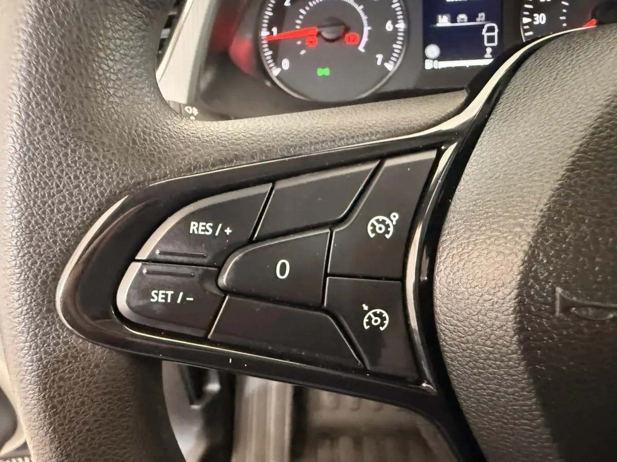 Gros plan sur les commandes au volant du Renault Kangoo 2022, boutons noirs avec fonctions régulateur de vitesse visibles.
