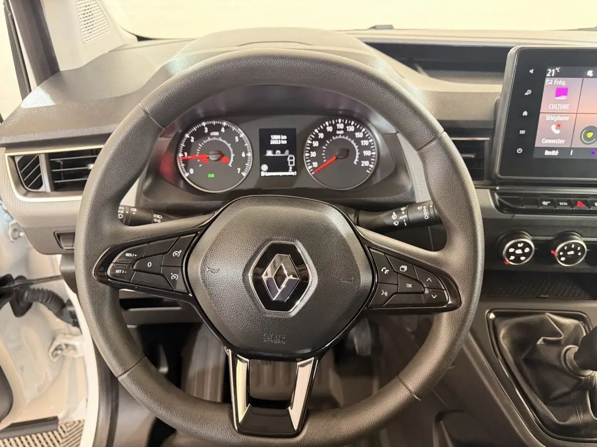 Vue intérieure centrée sur le volant noir du Renault Kangoo blanc 2022 avec tableau de bord et levier de vitesse manuel.