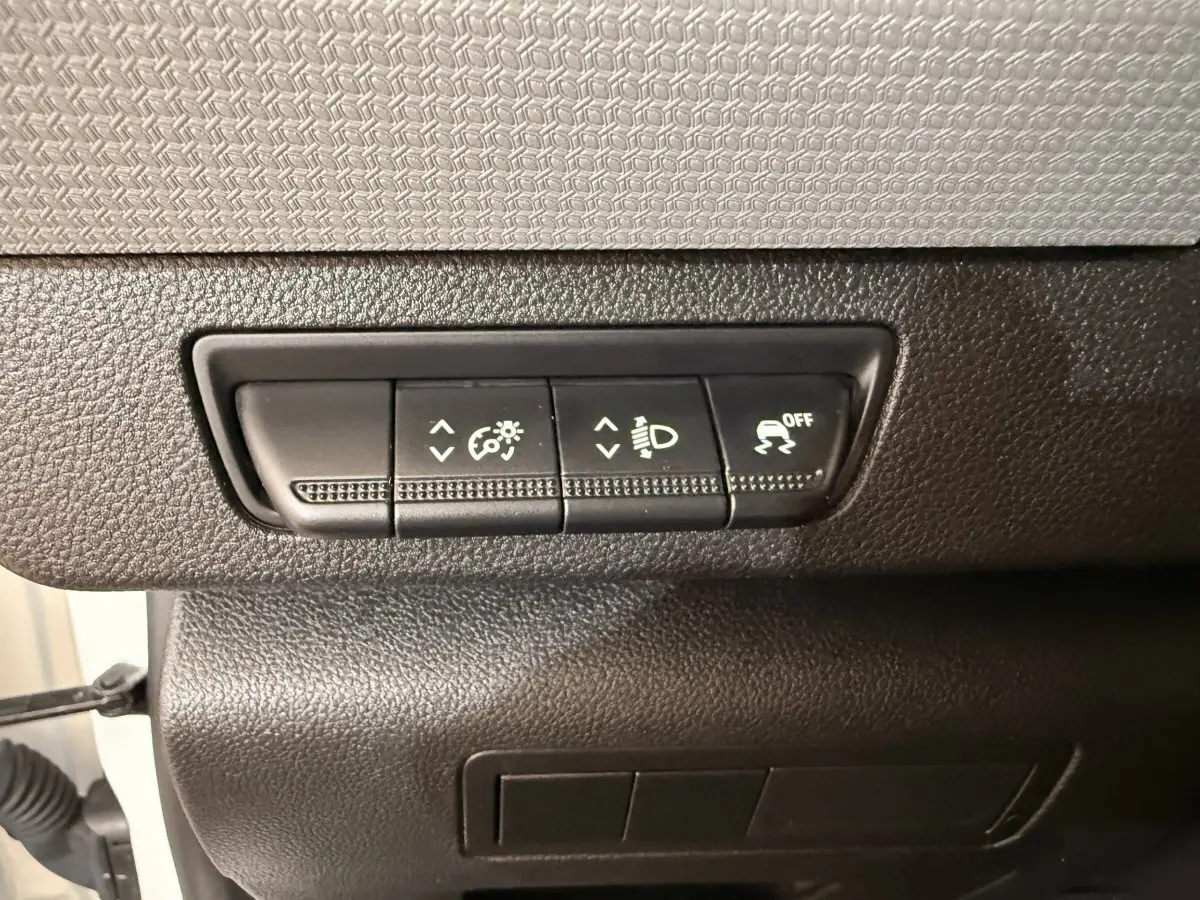 Gros plan sur les commandes de réglage d’éclairage et de traction du tableau de bord d’un Renault Kangoo blanc de 2022.