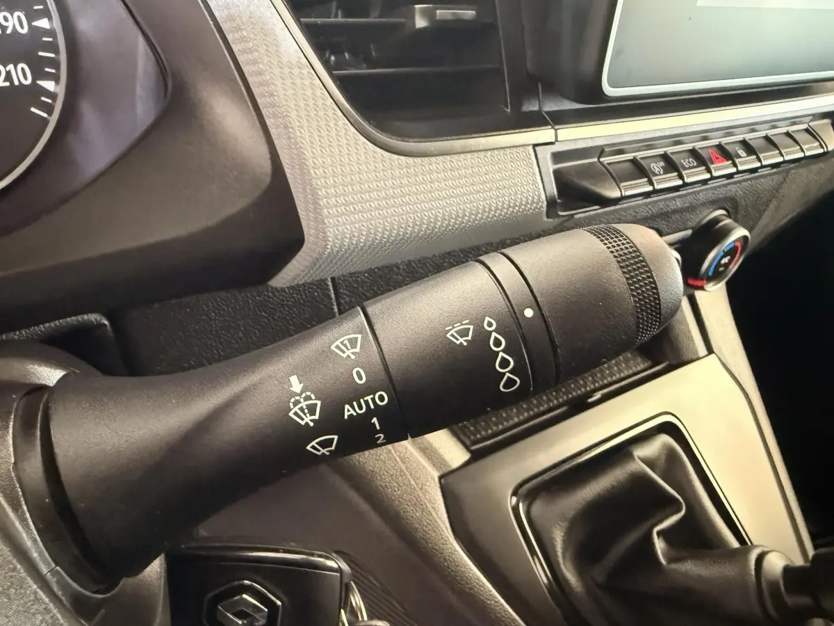Gros plan sur la commande d’essuie-glace et levier de vitesse manuelle dans l’habitacle d’un Renault Kangoo blanc 2022.