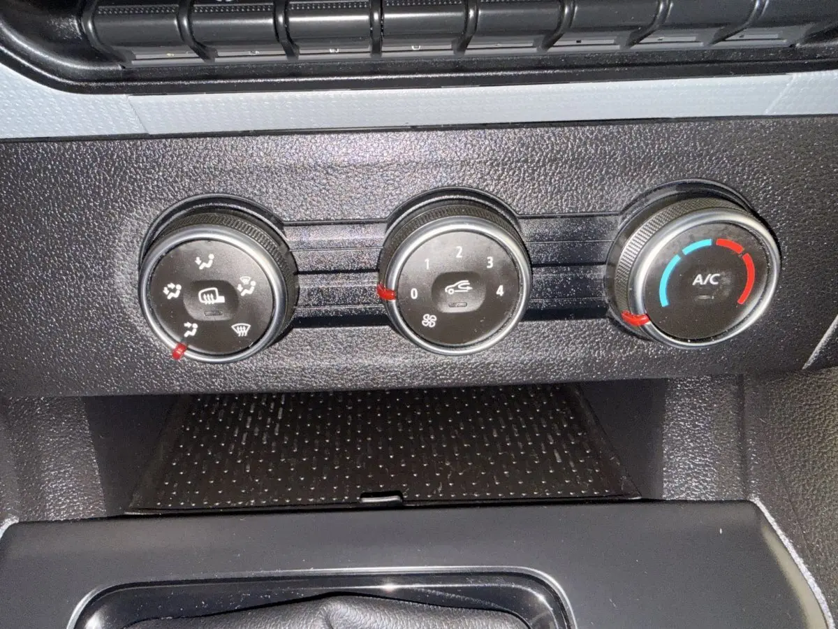 Gros plan sur les commandes de climatisation noires du Renault Kangoo blanc 2022, avec réglages manuels visibles.
