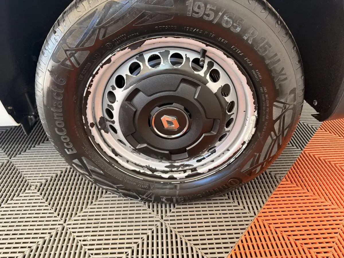 Gros plan sur la roue avant droite d’un Renault Kangoo blanc 2022, jante acier avec peinture écaillée et pneu Continental.
