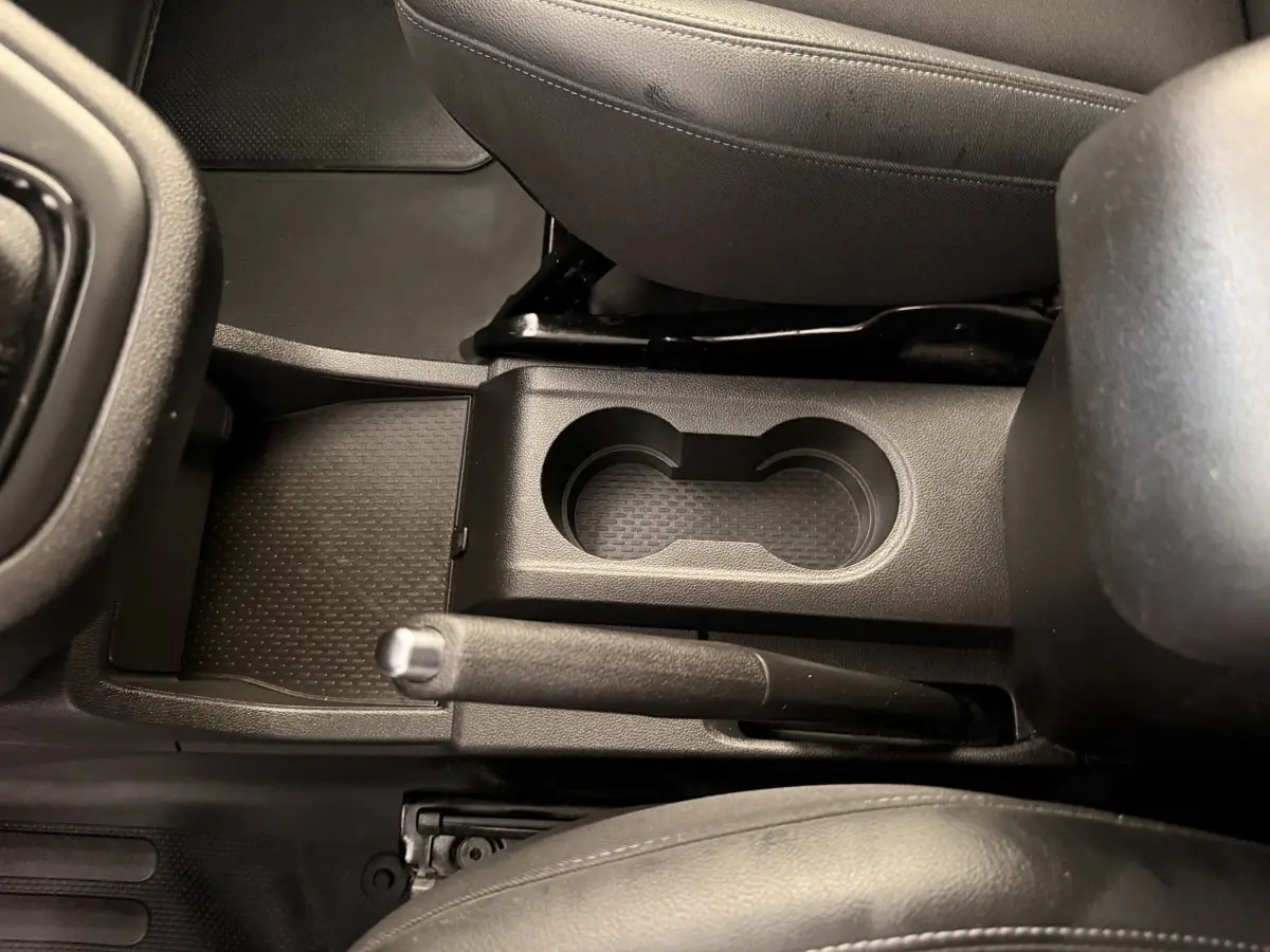 Vue rapprochée de la console centrale noire du Renault Kangoo 2022, montrant le frein à main manuel et deux porte-gobelets.