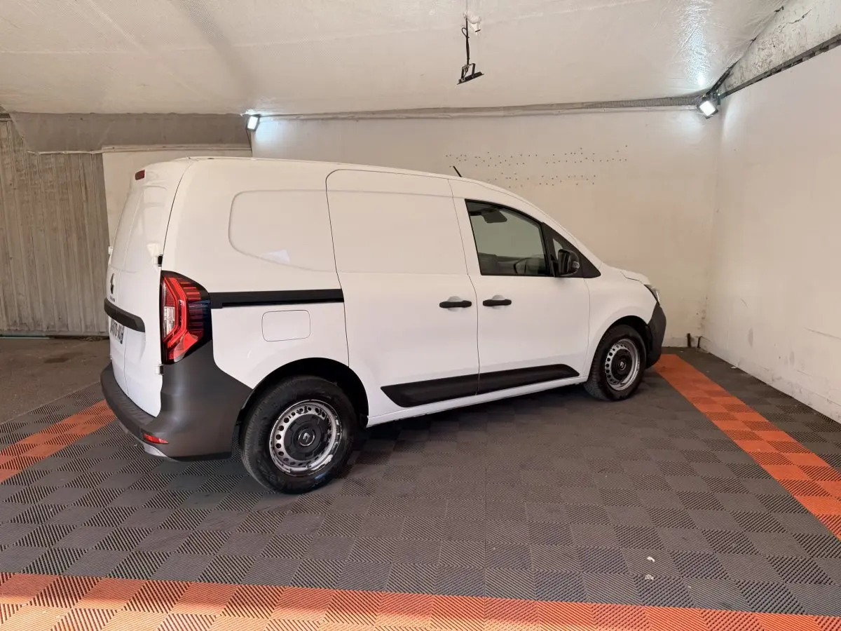 Renault Kangoo blanc vue de profil droit en intérieur, fourgonnette utilitaire avec protections noires sur les bas de caisse.