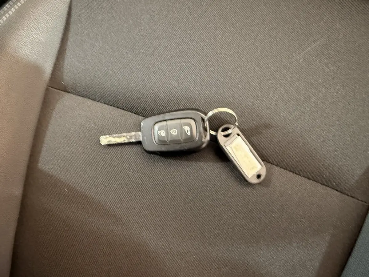 Clé de voiture Renault Kangoo 2022 posée sur un siège en tissu noir, sans vue du véhicule visible.