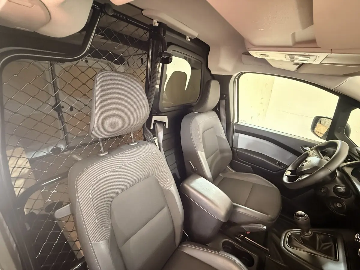 Vue intérieure côté conducteur du Renault Kangoo 2022, montrant les sièges gris et la cloison métallique séparatrice.