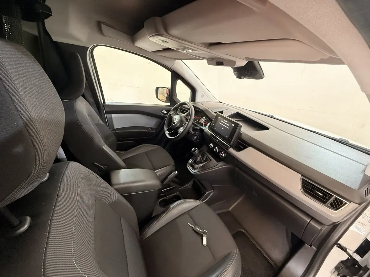 Vue intérieure côté passager du Renault Kangoo 2022, montrant les sièges noirs et la console avec écran tactile.