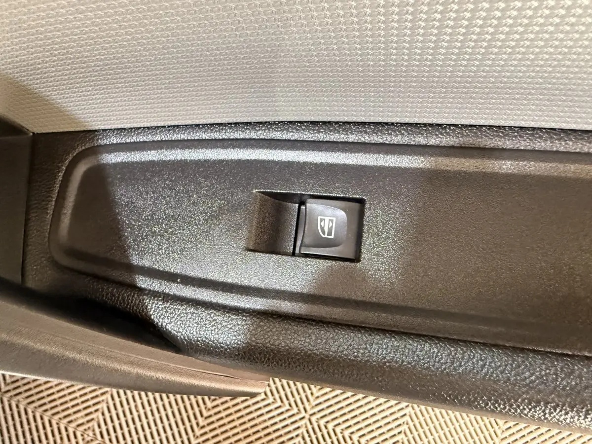 Bouton de commande de lève-vitre électrique sur la porte intérieure d'un Renault Kangoo blanc, vue rapprochée.