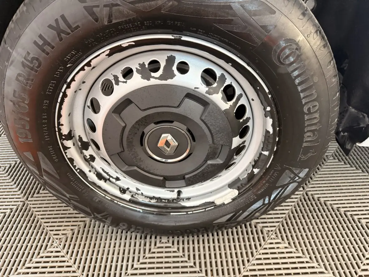 Gros plan sur la roue avant droite d’un Renault Kangoo blanc 2022, jante acier avec peinture écaillée.