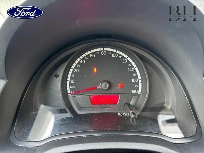 Vue rapprochée du compteur de vitesse d'une Volkswagen Up blanche, affichant 0 km/h avec voyants d'alerte allumés.