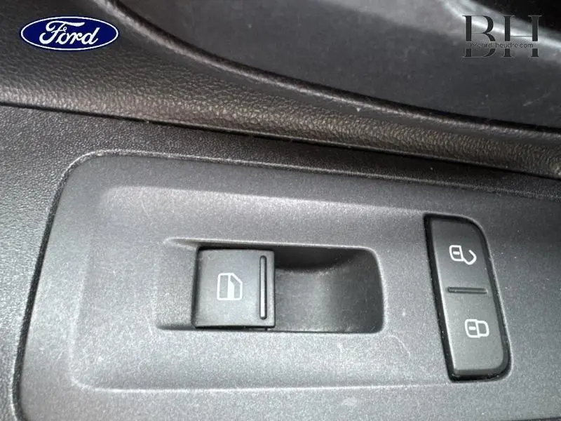 Gros plan sur les commandes de verrouillage et de lève-vitre côté conducteur d'une Volkswagen Up blanche.