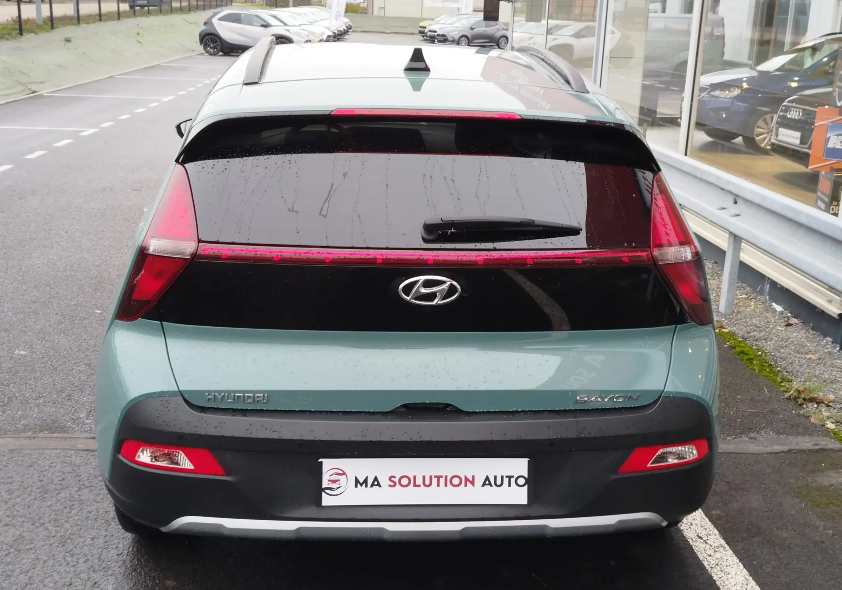 Vue arrière d’un Hyundai Bayon 2022 couleur Elemental Brass Metal avec feux arrière en bandeau et lunette arrière teintée.