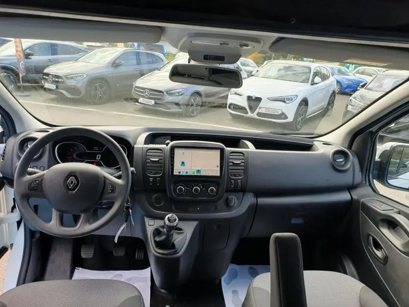 Vue intérieure avant du Renault Trafic Fourgon blanc Glacier, montrant le tableau de bord avec écran tactile et boîte manuelle.