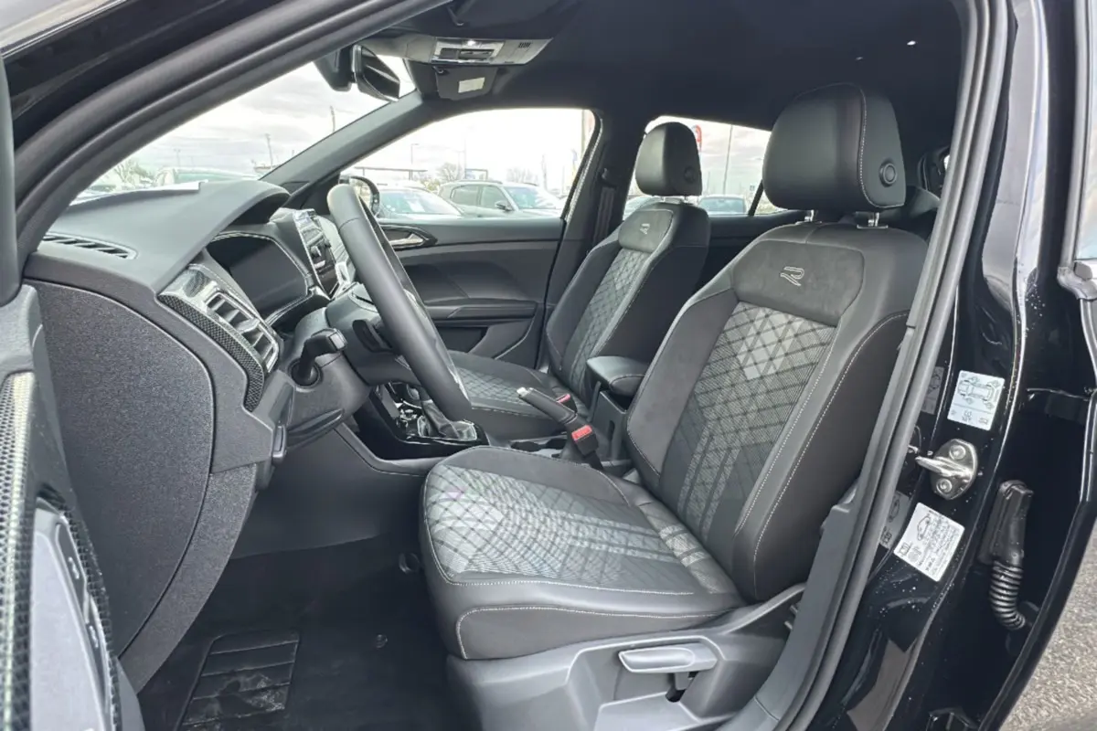 Vue intérieure côté conducteur du Volkswagen T-Cross noir intense, sièges R-Line en tissu et alcantara avec surpiqûres contrastées.