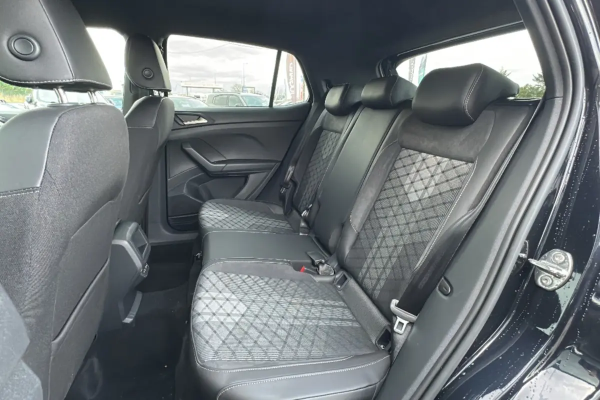 Vue intérieure côté droit montrant la banquette arrière tissu noir avec motifs géométriques du Volkswagen T-Cross noir intense 2025.