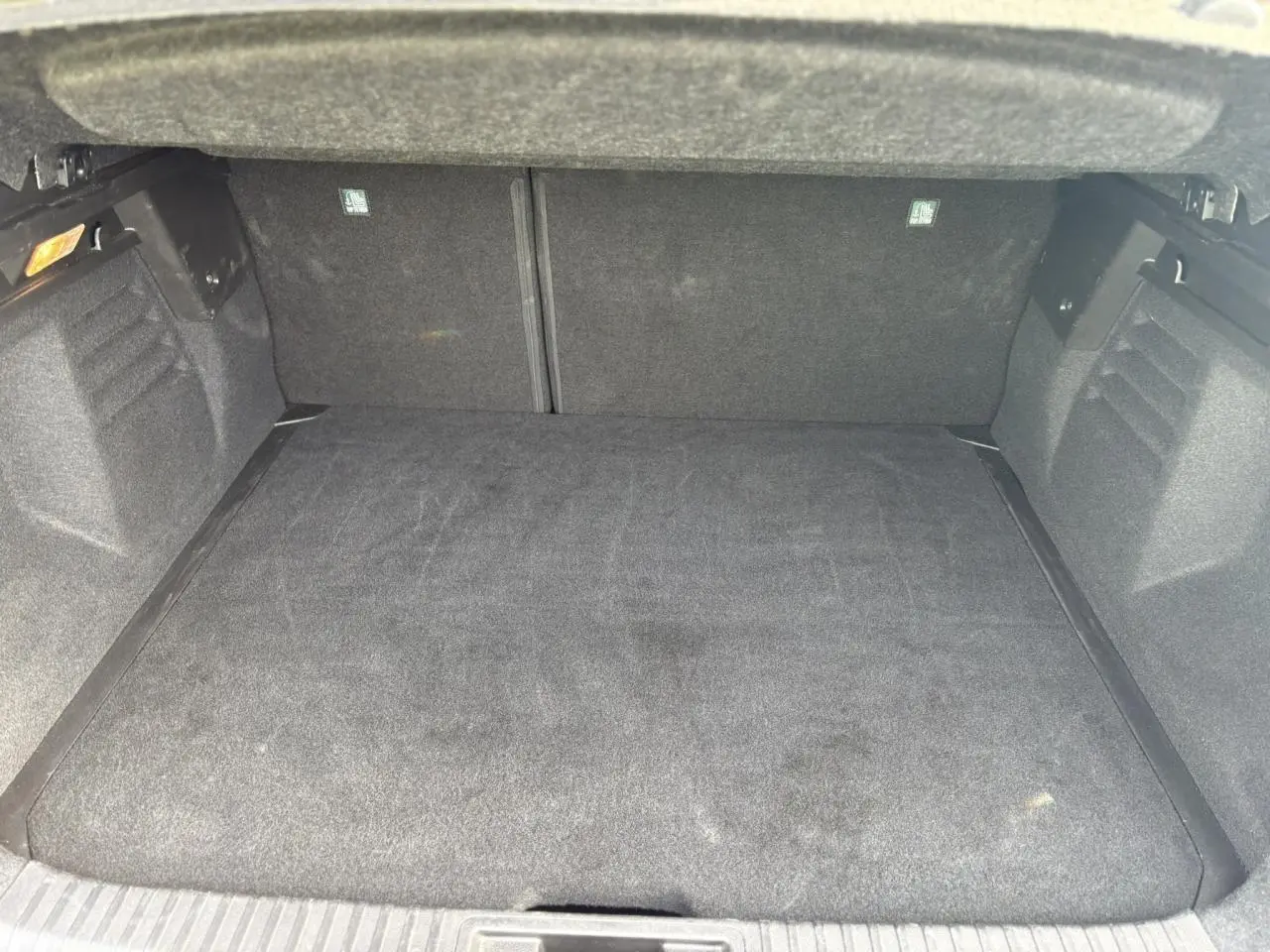 Coffre ouvert vu de l'arrière, intérieur spacieux et tapis de sol noir du Renault Symbioz bleu Iron 2025.