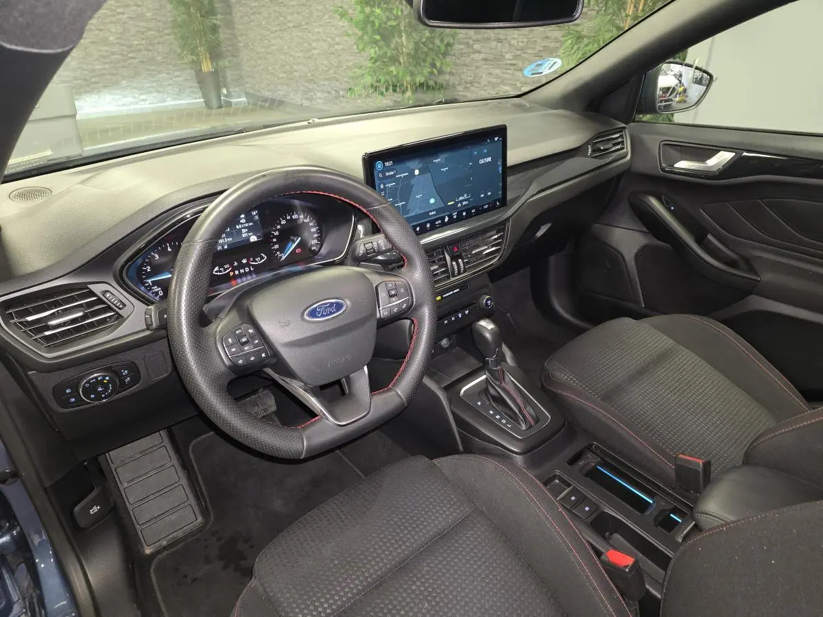 Vue intérieure avant droite de la Ford Focus 2024, volant ST à surpiqûres rouges et écran tactile 13 pouces.