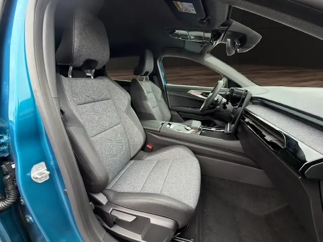 Vue intérieure côté conducteur du Renault Austral bleu, montrant les sièges tissu et cuir, le tableau de bord moderne et l’écran tactile central.