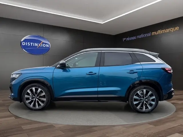 Profil droit du Renault Austral 2026 bleu bi-ton avec toit blanc et jantes alliage RS visibles en showroom.