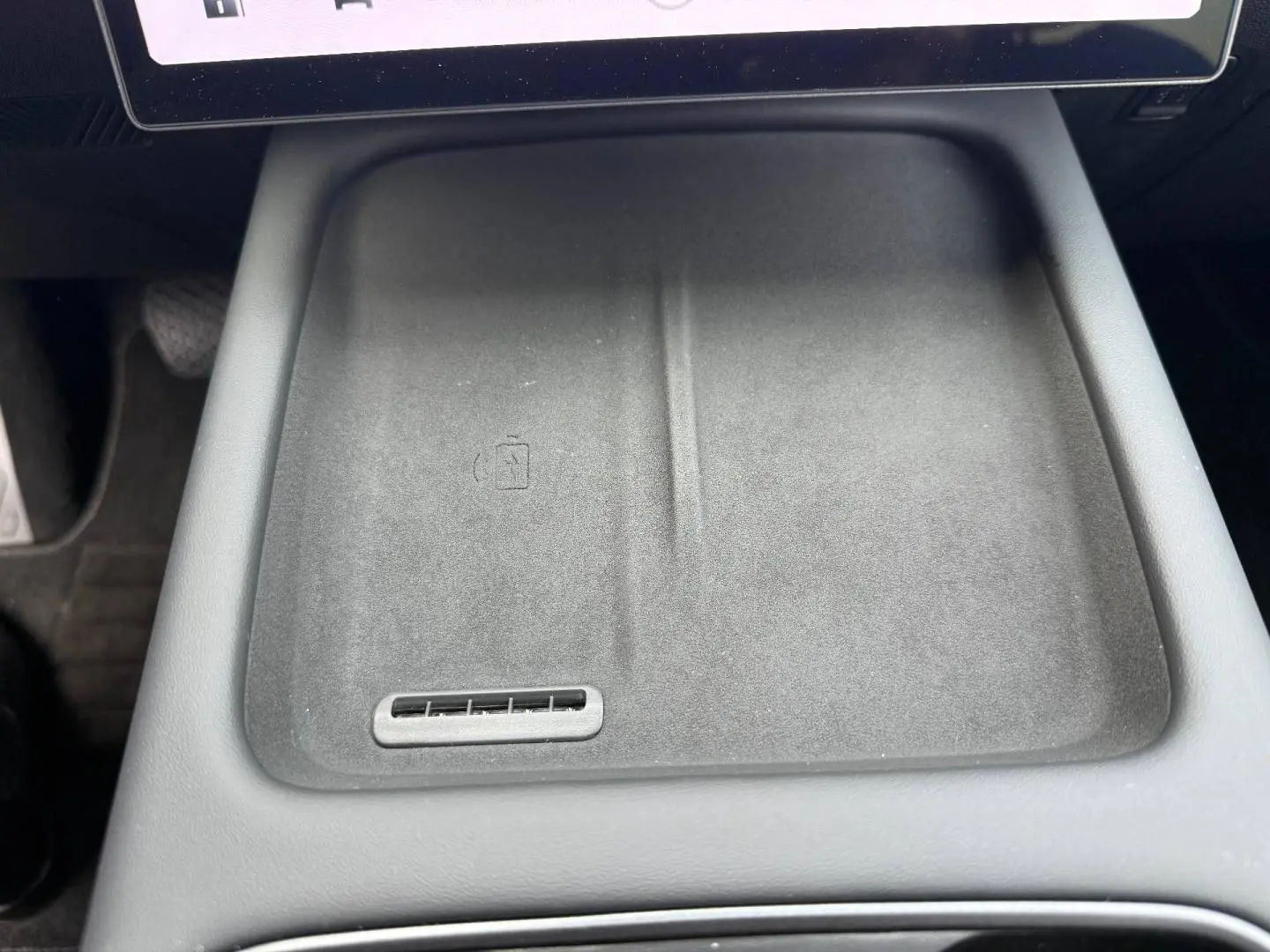 Gros plan sur le plateau de recharge sans fil noir mat au centre de la console intérieure du JAECOO J7 2026.
