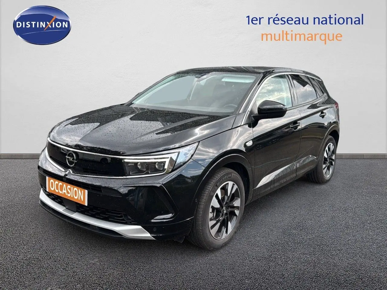 Opel Grandland noir en 3/4 avant droit, hybride rechargeable, jantes bi-ton et calandre moderne sous la pluie.