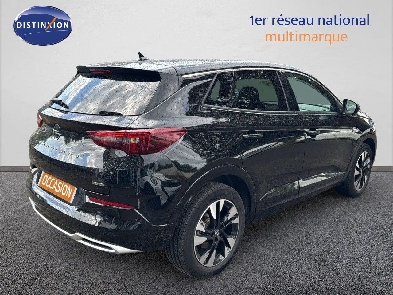 Opel Grandland noir en 3/4 arrière droit, hybride rechargeable, jantes bi-ton et feux arrière LED visibles.