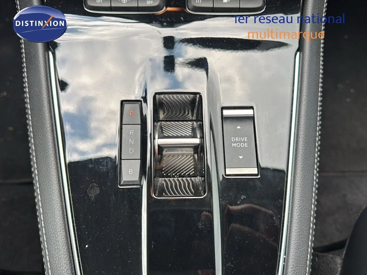 Vue rapprochée de la console centrale noire brillante de l'Opel Grandland 2024 avec sélecteur de boîte auto et bouton Drive Mode.