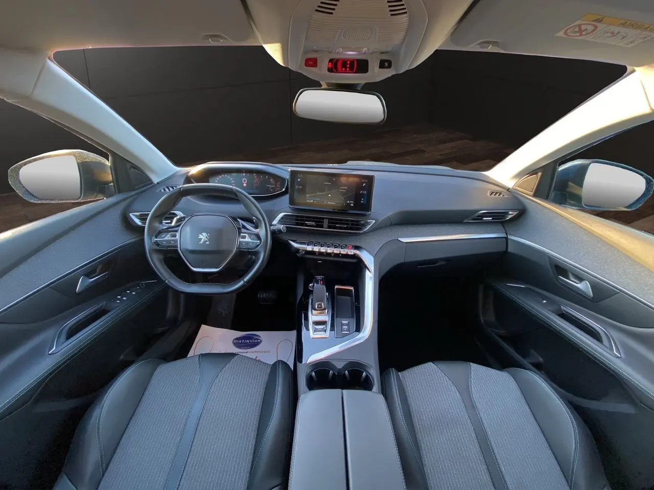 Vue intérieure avant du Peugeot 3008 2021 avec tableau de bord moderne et sièges tissu gris noir.