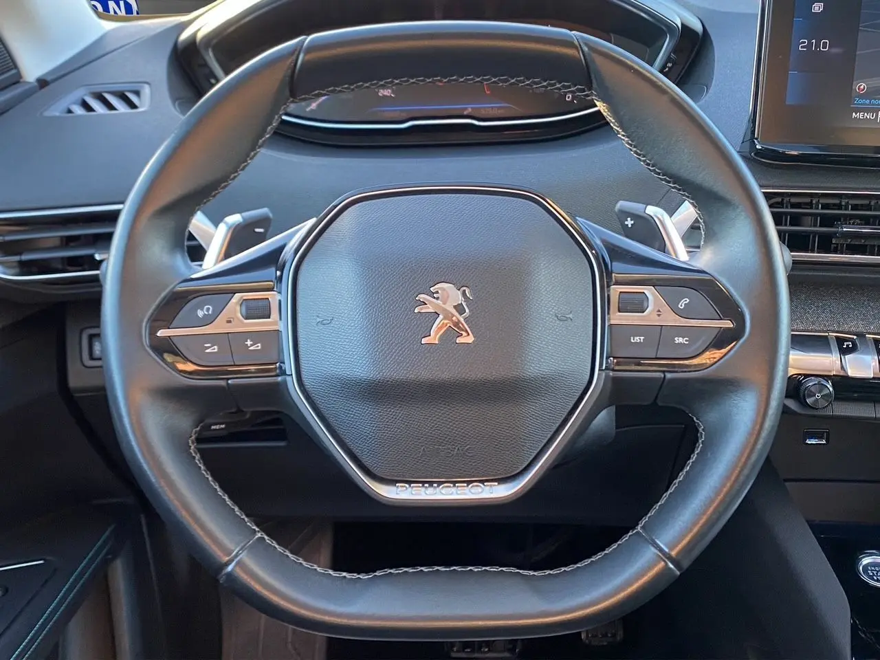 Vue rapprochée du volant cuir noir du Peugeot 3008 2021 avec commandes intégrées et tableau de bord numérique.