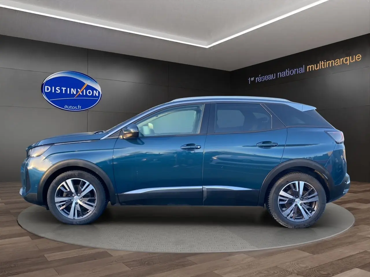 Vue de profil côté gauche d’un Peugeot 3008 Bleu Célèbes 2021 en showroom avec jantes alliage et toit noir.