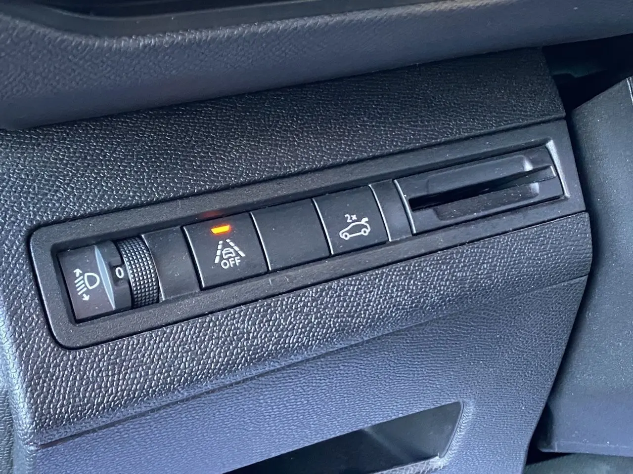 Gros plan sur les commandes intérieures noires du tableau de bord, avec bouton hayon main libre et témoin allumé.
