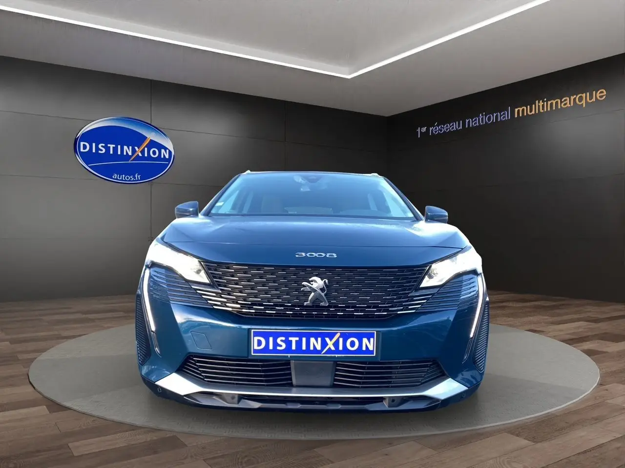 Peugeot 3008 Bleu Célèbes vue de face en intérieur, avec calandre distinctive et phares allumés.