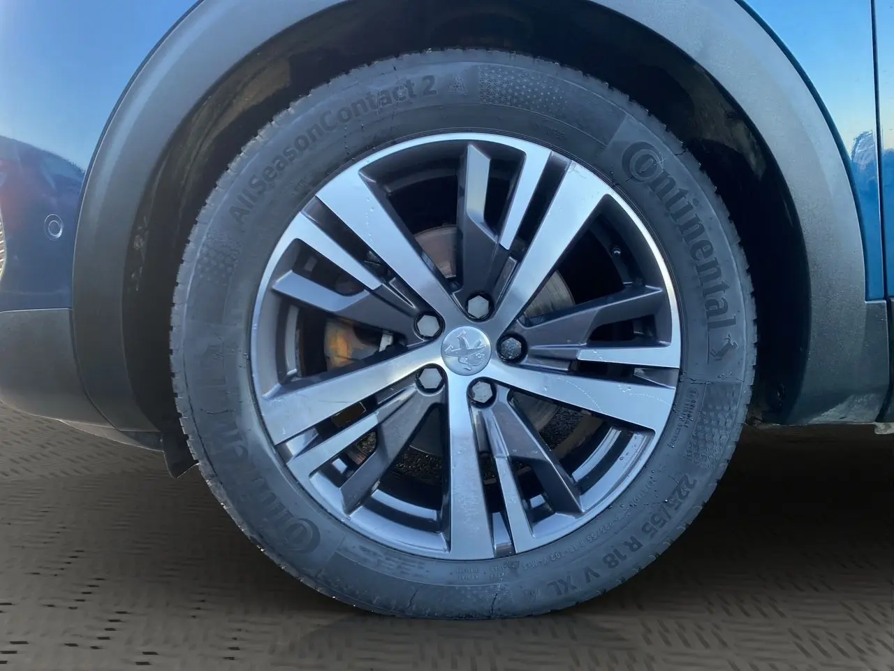 Gros plan sur la roue avant droite du Peugeot 3008 Bleu Célèbes, jante alliage à design moderne.