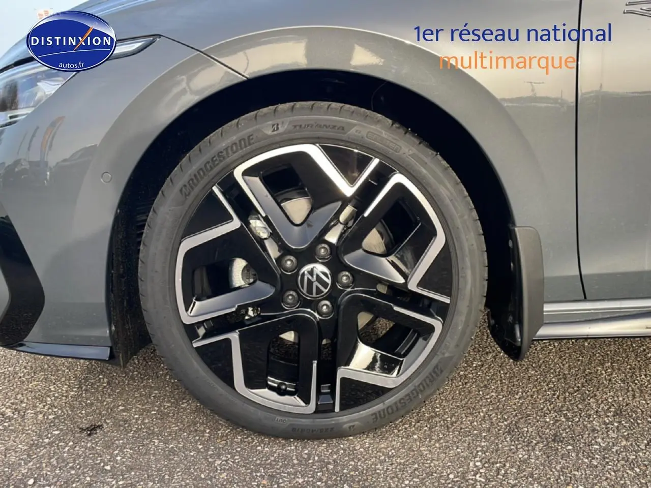 Gros plan sur la roue avant gauche d'une Volkswagen Golf gris métallisé avec jante alu noire et argent.