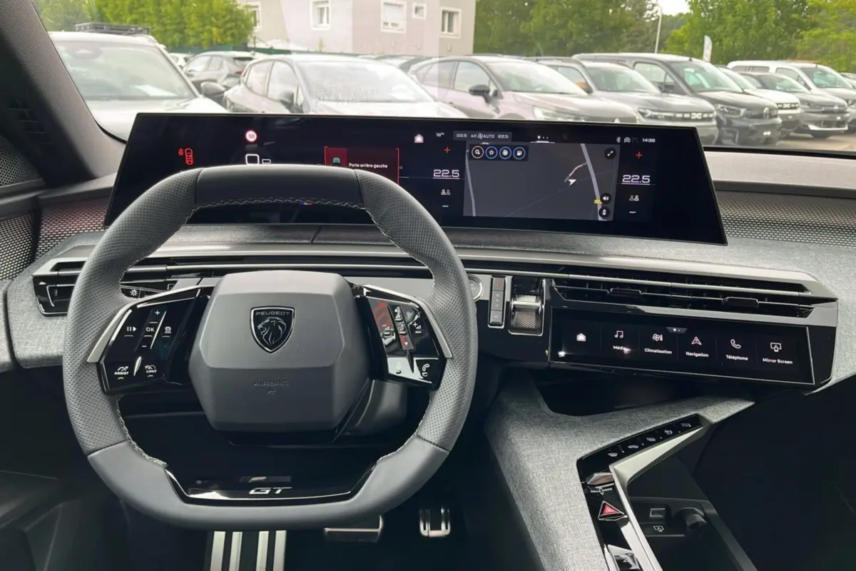Vue intérieure centrée sur le volant cuir multifonctions et le tableau de bord numérique du Peugeot 5008 Hybrid GT.