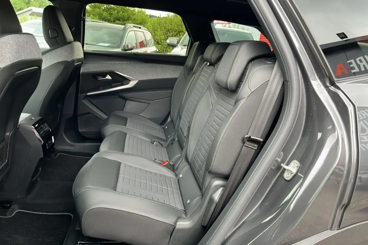 Vue côté droit sur la banquette arrière en cuir et tissu gris du Peugeot 5008 Hybrid 145 GT 2025 avec porte ouverte.