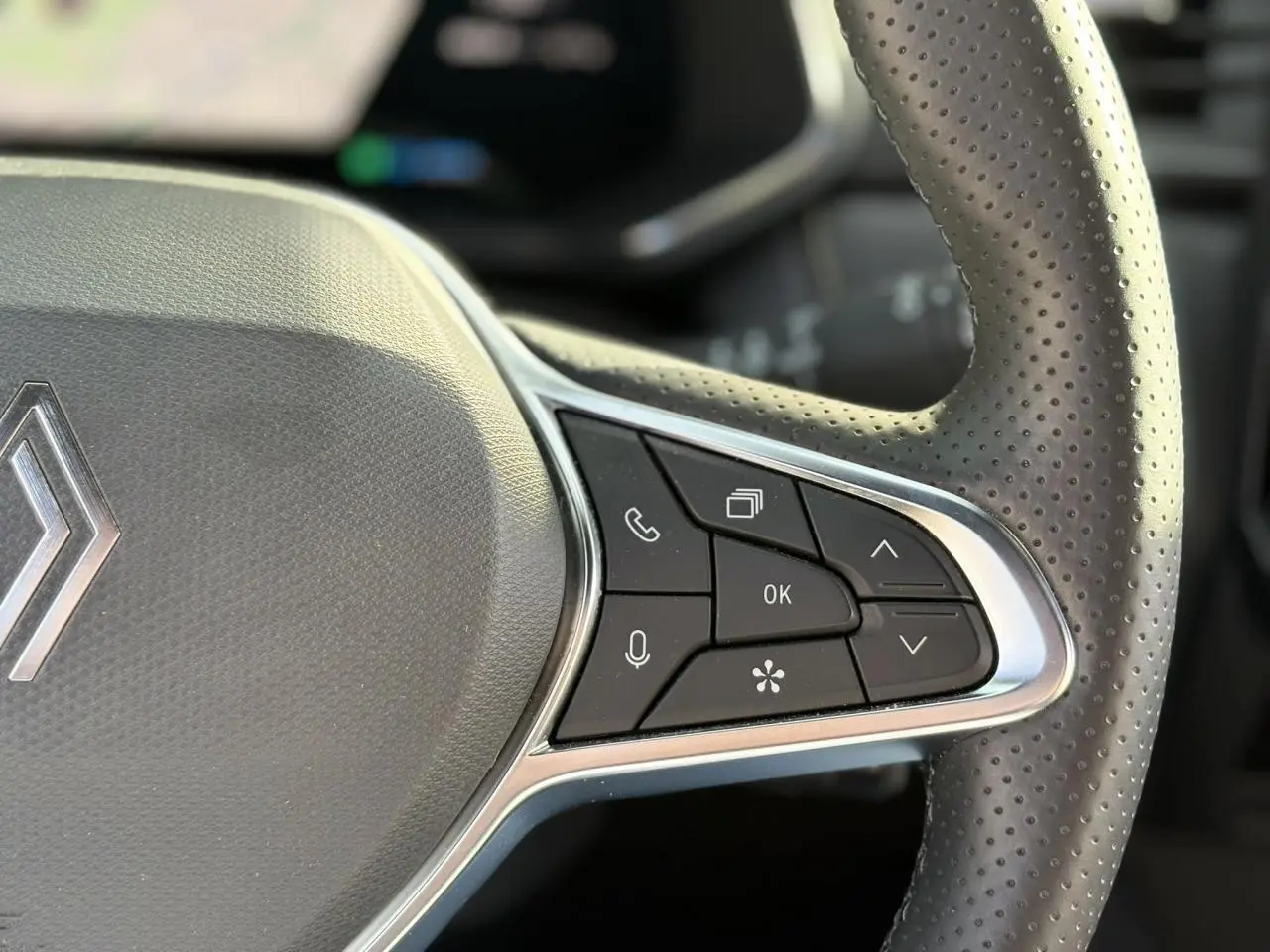 Gros plan sur la partie droite du volant en cuir perforé du Renault Symbioz gris, avec commandes multifonctions intégrées.