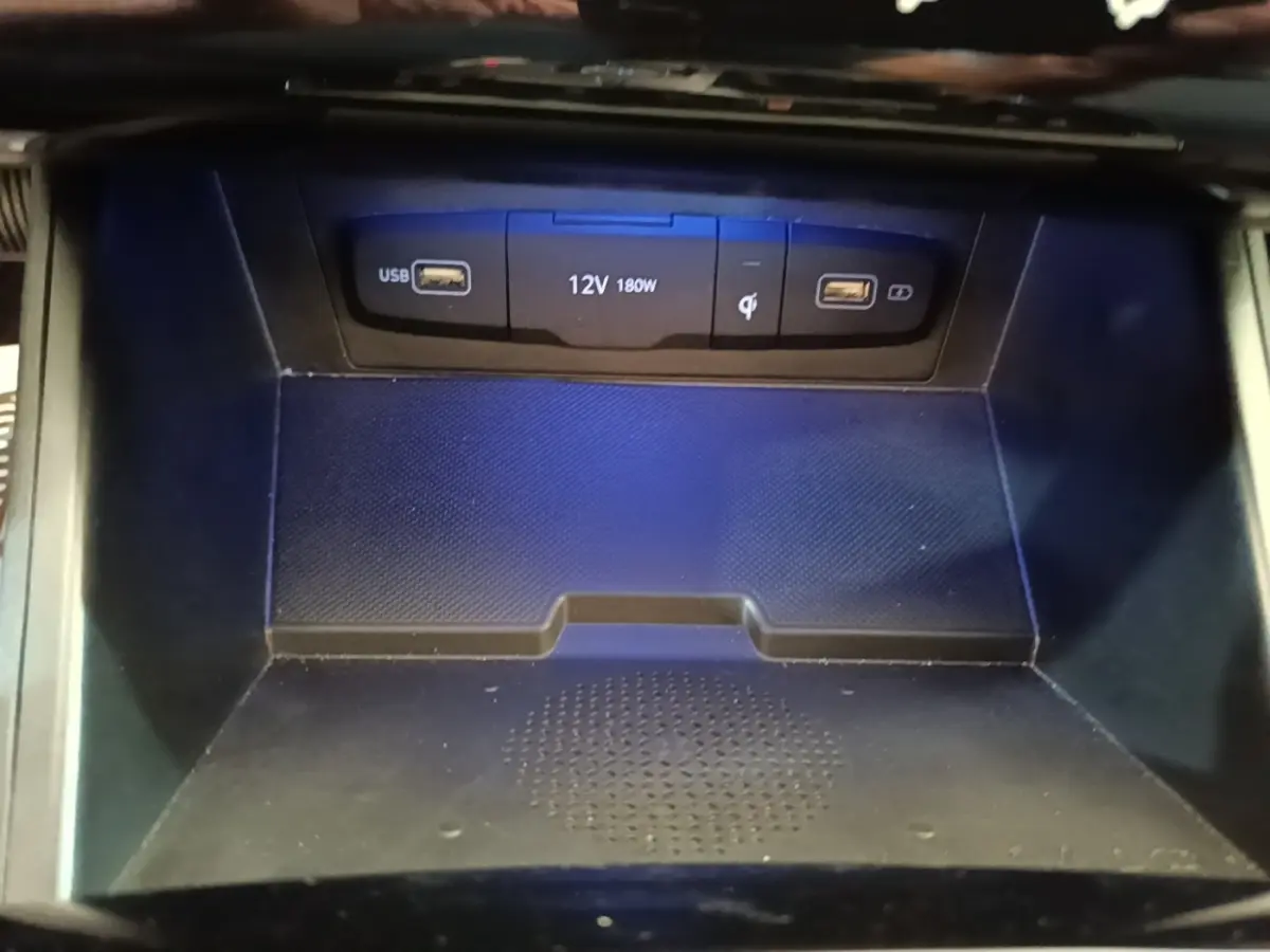 Gros plan sur la zone de recharge à induction noire avec ports USB et prise 12V dans une Hyundai Tucson 1.6 Hybrid 230 Executive.