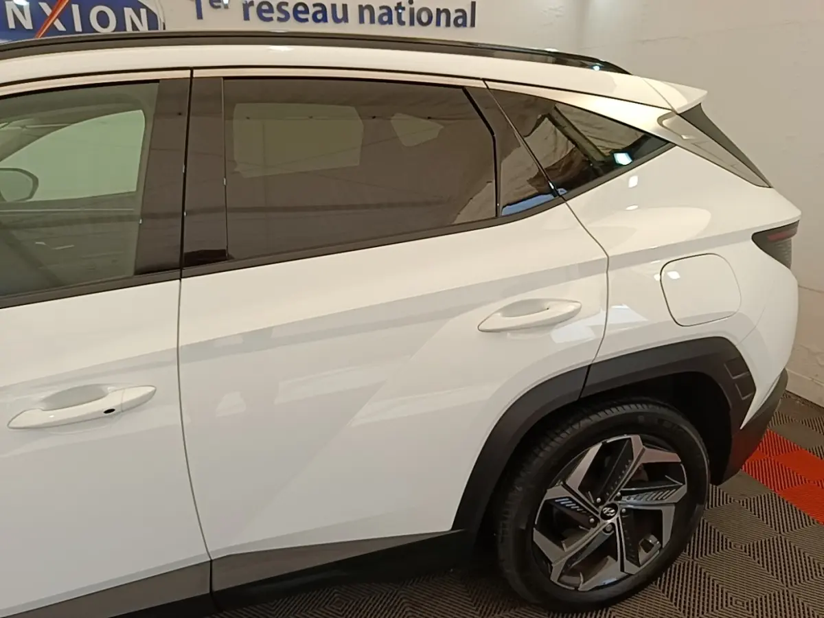 Vue latérale droite du Hyundai Tucson blanc 2022, mettant en valeur les vitres teintées et les jantes alliage distinctives.