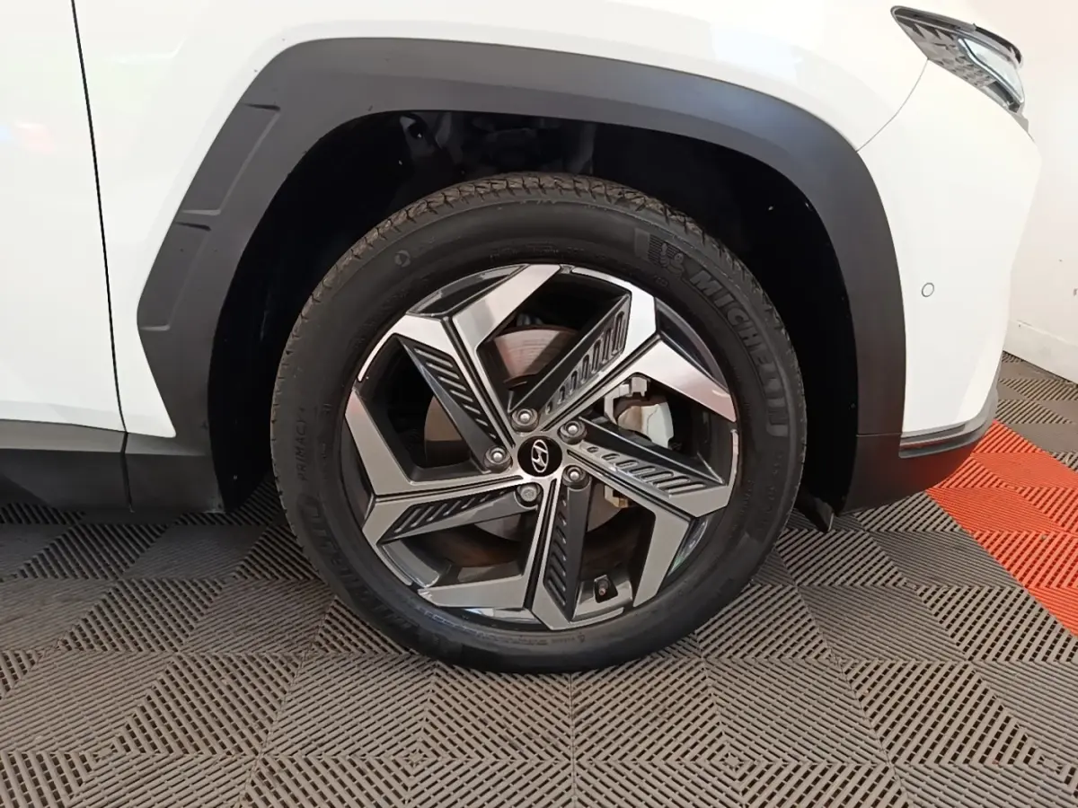 Gros plan sur la roue avant droite d’un Hyundai Tucson blanc 2022 avec jante alliage au design moderne.