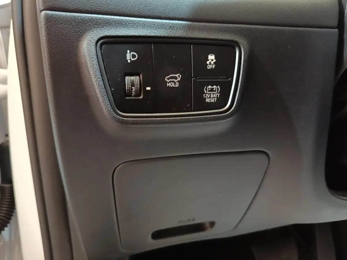 Vue rapprochée des commandes noires sur tableau de bord côté gauche du Hyundai Tucson blanc 1.6 Hybrid 230 Executive 2022.