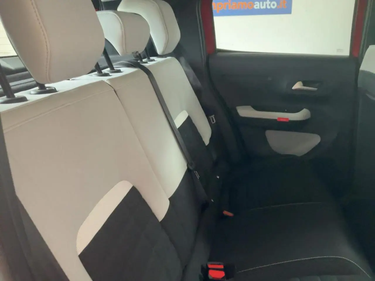Vue intérieure côté droit des sièges arrière bicolores beige et noir de la Citroën C3 ë-113 Berline Max 2025 rouge métal foncé.