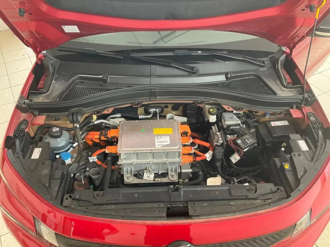 Vue plongeante sur le moteur électrique et câblage orange du Citroën C3 ë-113 Berline Max rouge métal 2025 avec capot ouvert.