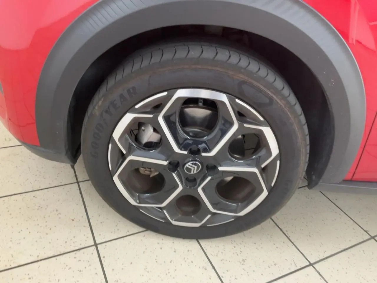 Gros plan sur la roue avant gauche d'une Citroën C3 ë-113 Berline Max 2025 rouge métal foncé avec jante noire et argent.