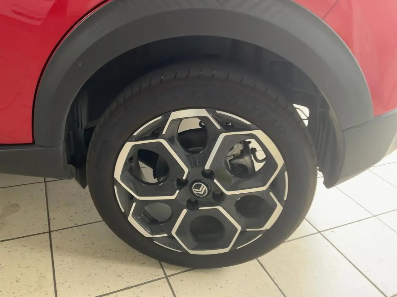 Gros plan sur la roue avant droite d'une Citroën C3 ë-113 Berline Max rouge métal foncé avec jante noire et argentée.
