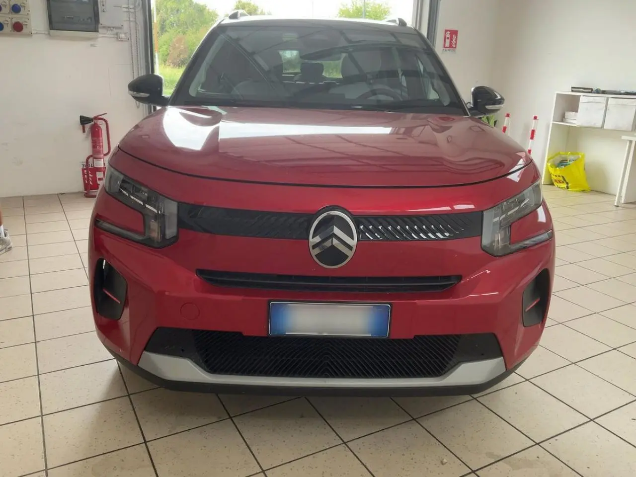 Vue avant d'une Citroën C3 ë-113 Berline Max rouge métal foncé, avec calandre noire et logo Citroën central.