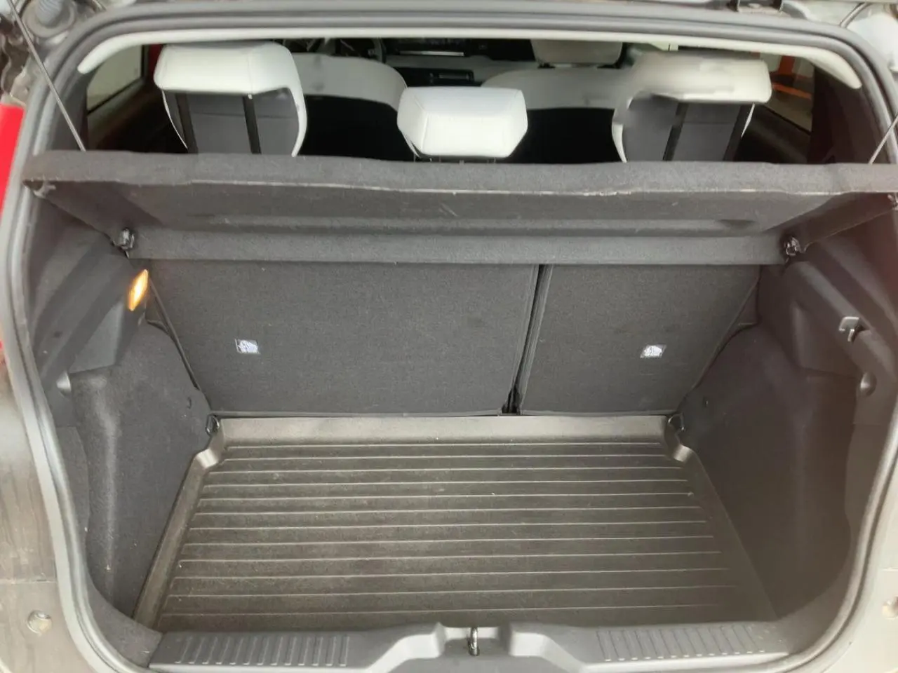 Coffre ouvert vu de l'arrière d'une Citroën C3 ë-113 Berline Max 2025 rouge métal foncé, intérieur noir.