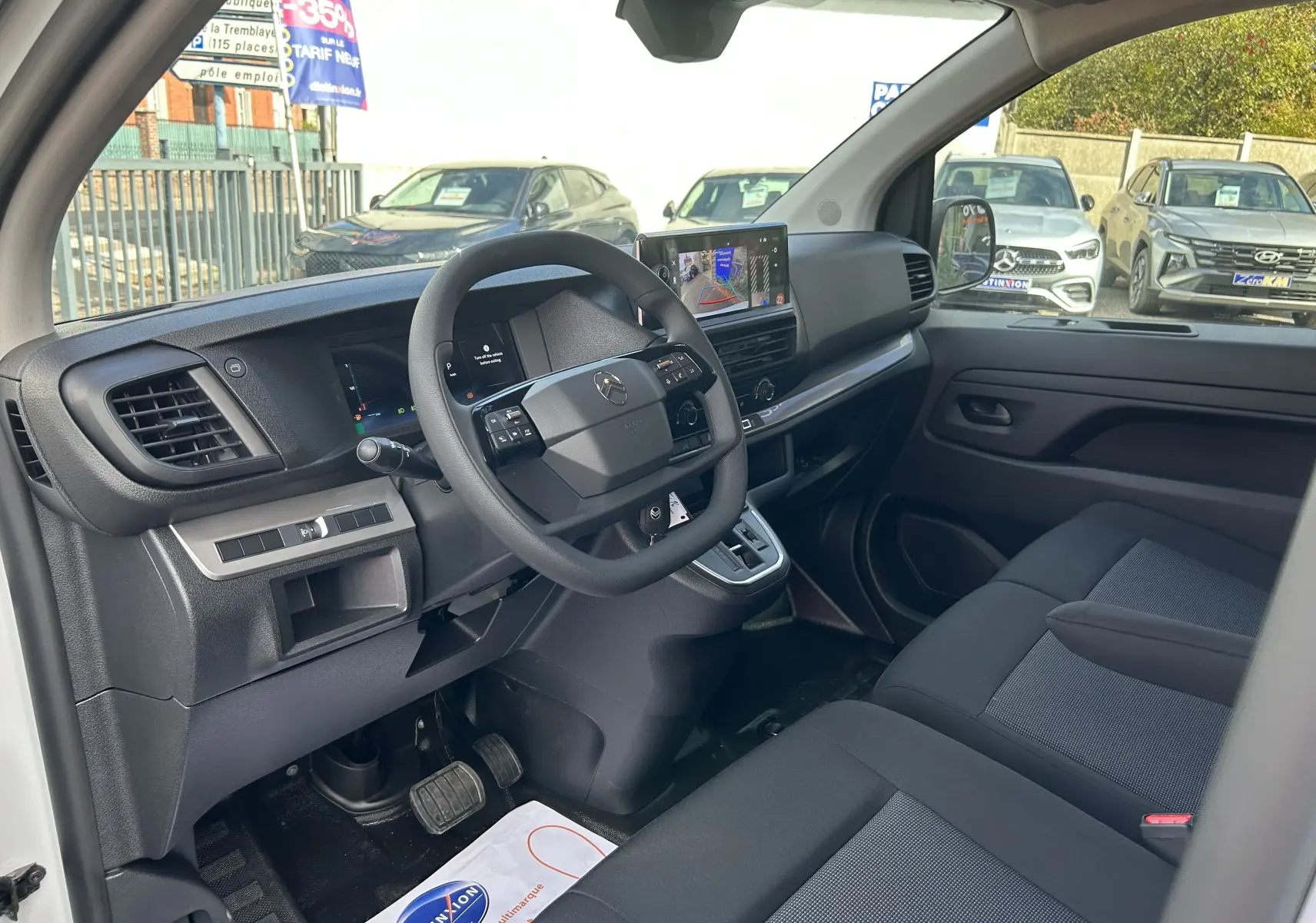Vue intérieure côté conducteur du fourgon blanc Citroën Jumpy 2025, avec tableau de bord moderne et écran tactile central.
